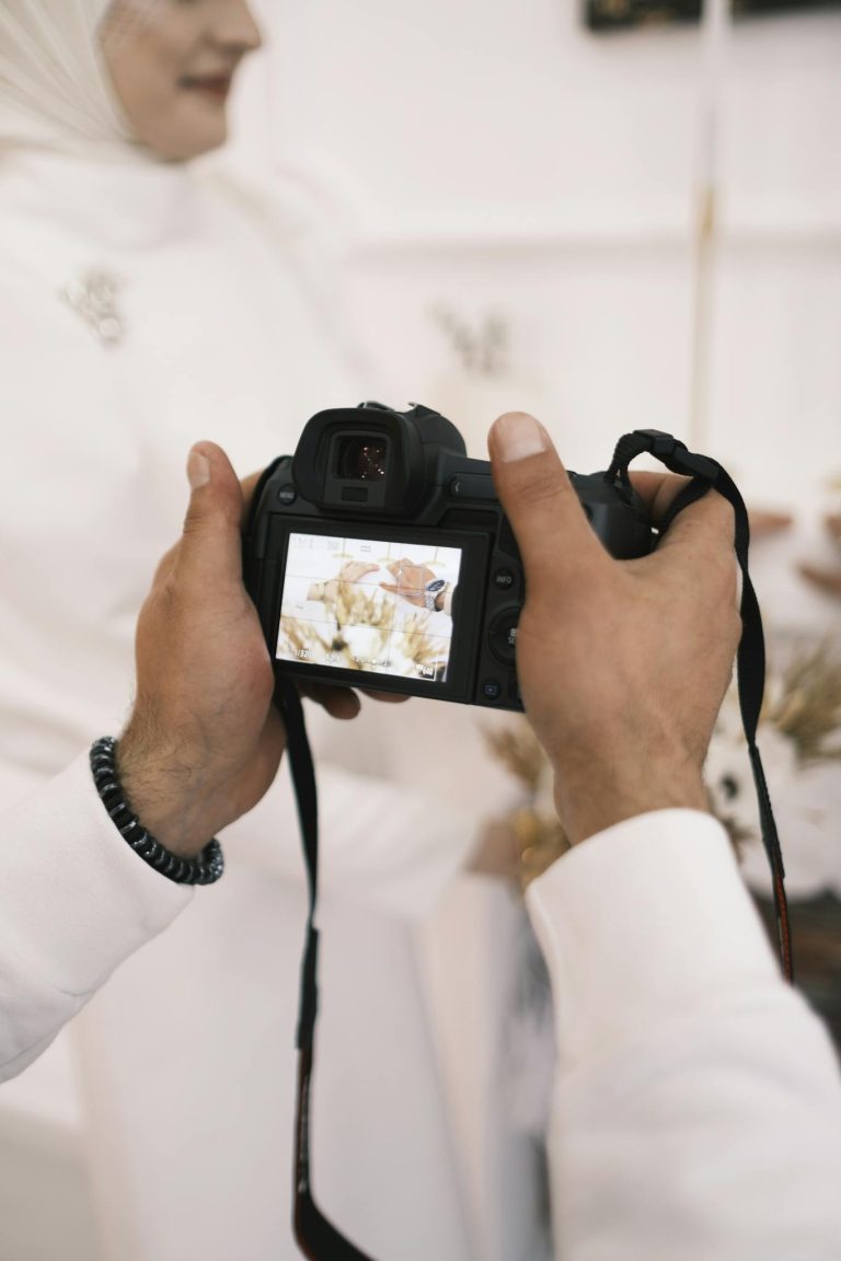 Close-up of a photographer's hands capturing wedding details with a digital camera.
