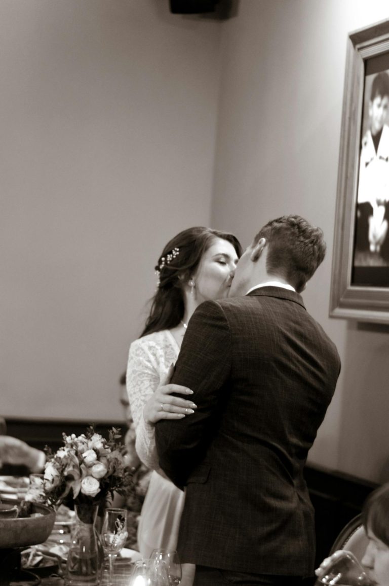 Emotional moment of a couple kissing at their wedding reception in black and white.